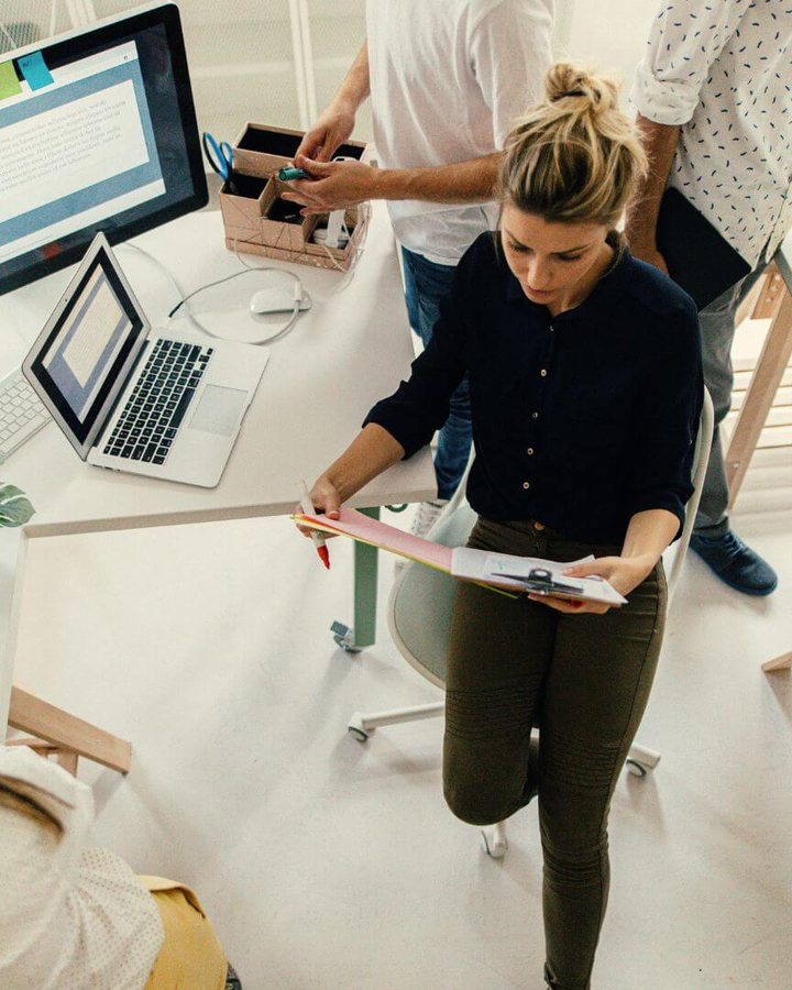 Team i strategimöte om innovation, en kvinna går igenom anteckningar vid skrivbordet